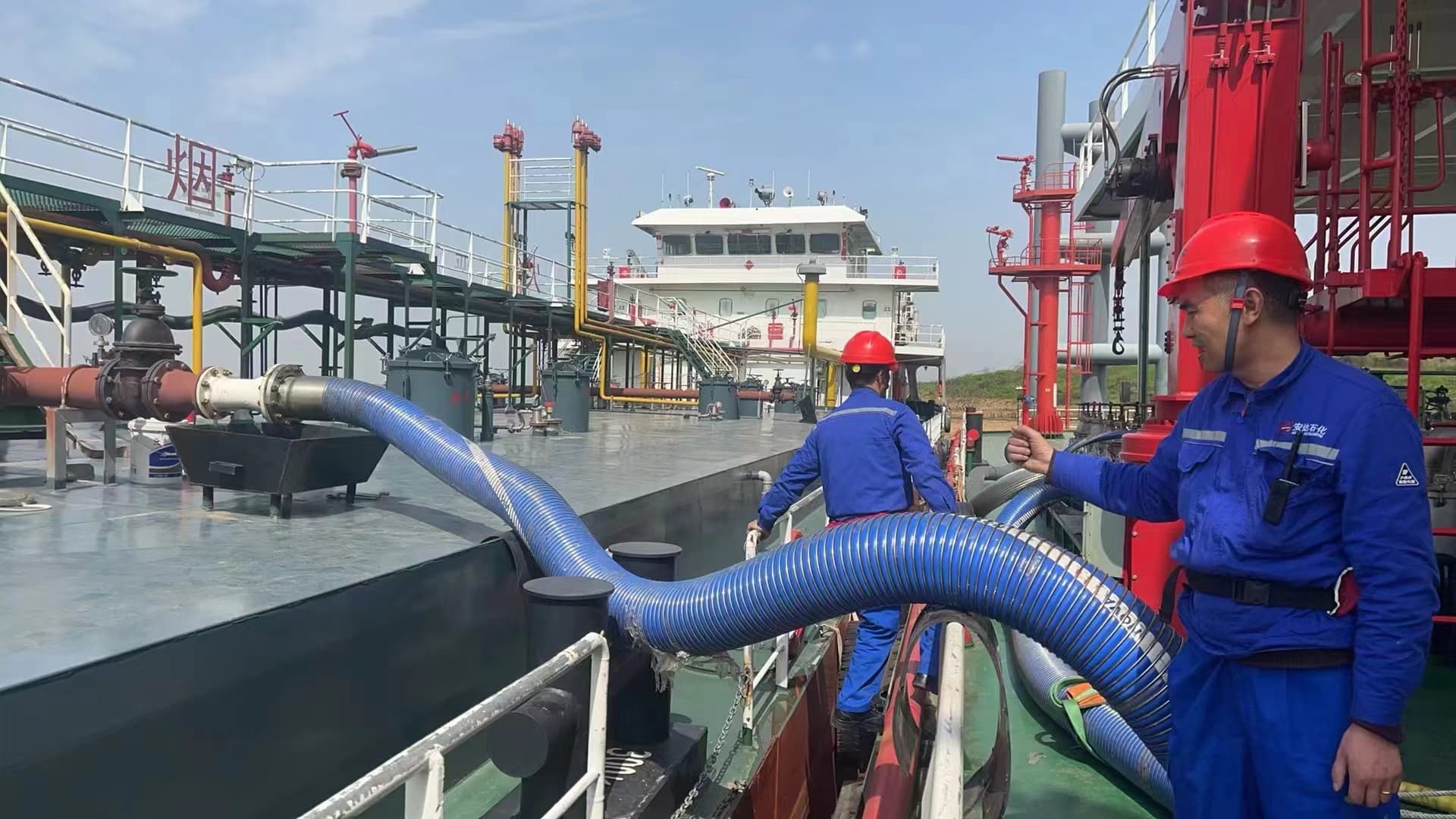 Composite hose transfer operation with workers on vessel